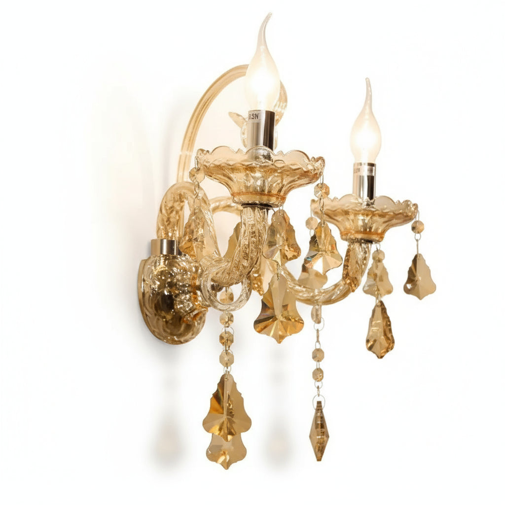 Gold crystal wall sconce with two lights on a beige wall.