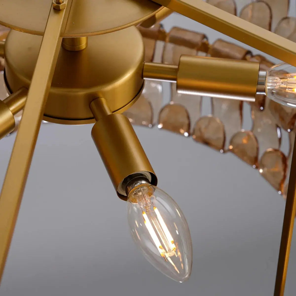 Gold ceiling light fixture with clear bulb on a gray background