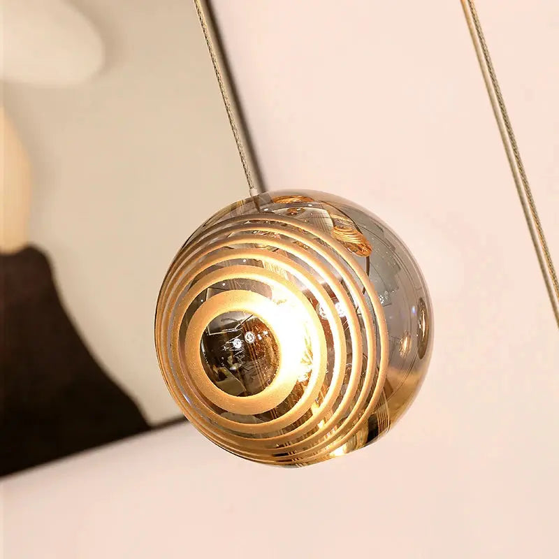 Pendant light with clear glass shade and gold interior on a neutral background