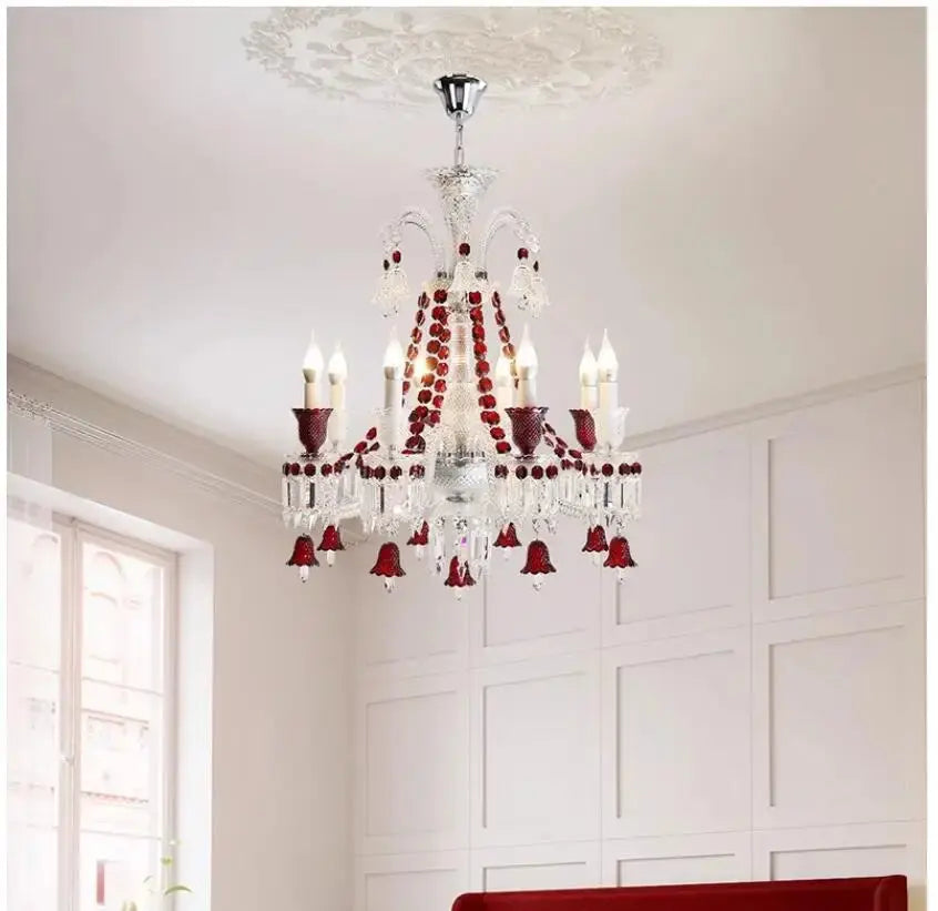 Chandelier with red accents hanging in a room with white walls and a window.