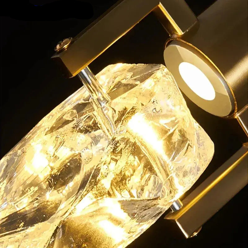 Close-up of an illuminated irregular crystal shade held beneath a gold-toned cylindrical light fitting.