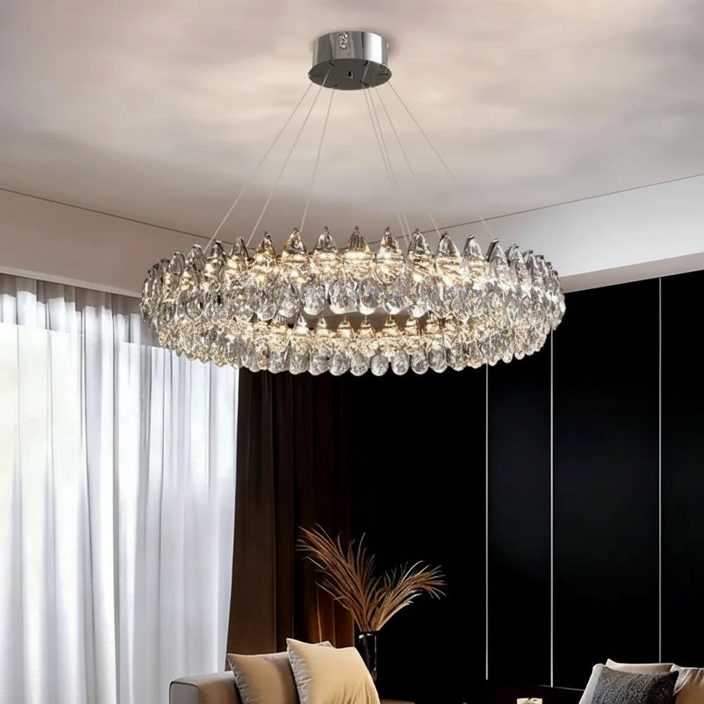 Crystal chandelier hanging in a room with curtains and a plant.
