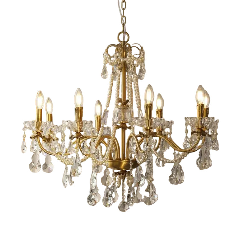 Gold chandelier with crystal accents hanging in a room with a painting and plant.