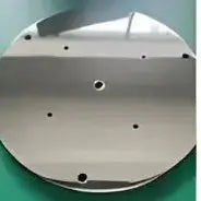 Four circular metal objects in gold, white, black, and silver on a green background.