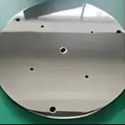 Four circular metal objects in gold, white, black, and silver on a green background.