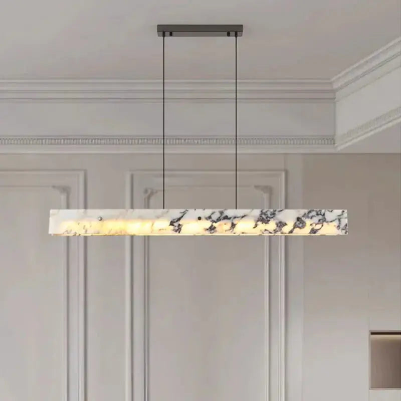 Modern pendant light fixture hanging in a room with white walls and ceiling.
