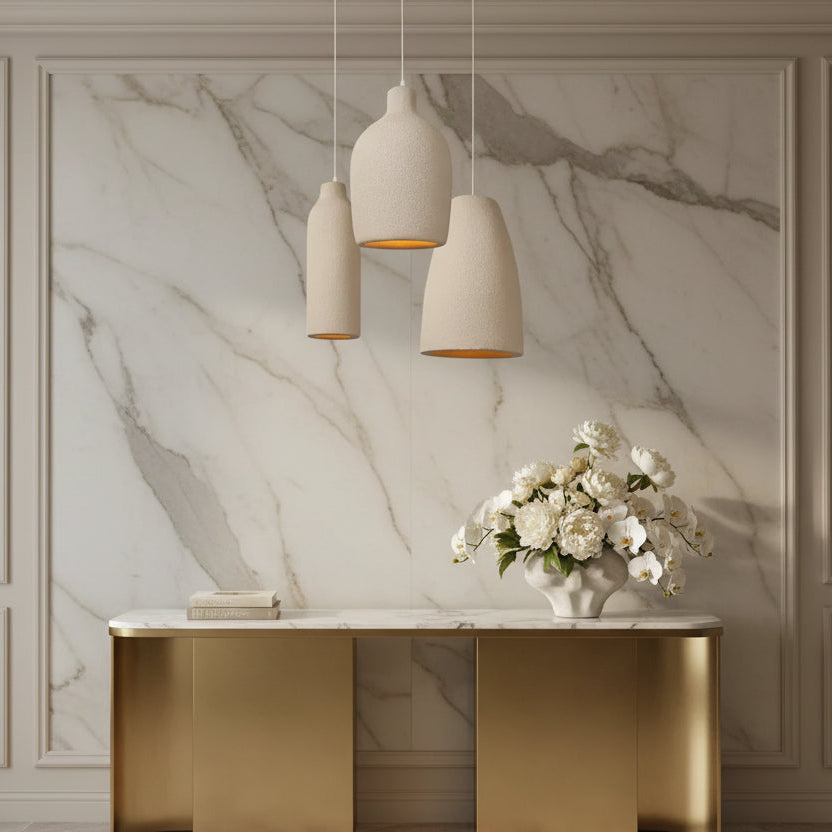 Decorative interior setting with a marble wall, gold console table, and floral arrangement.