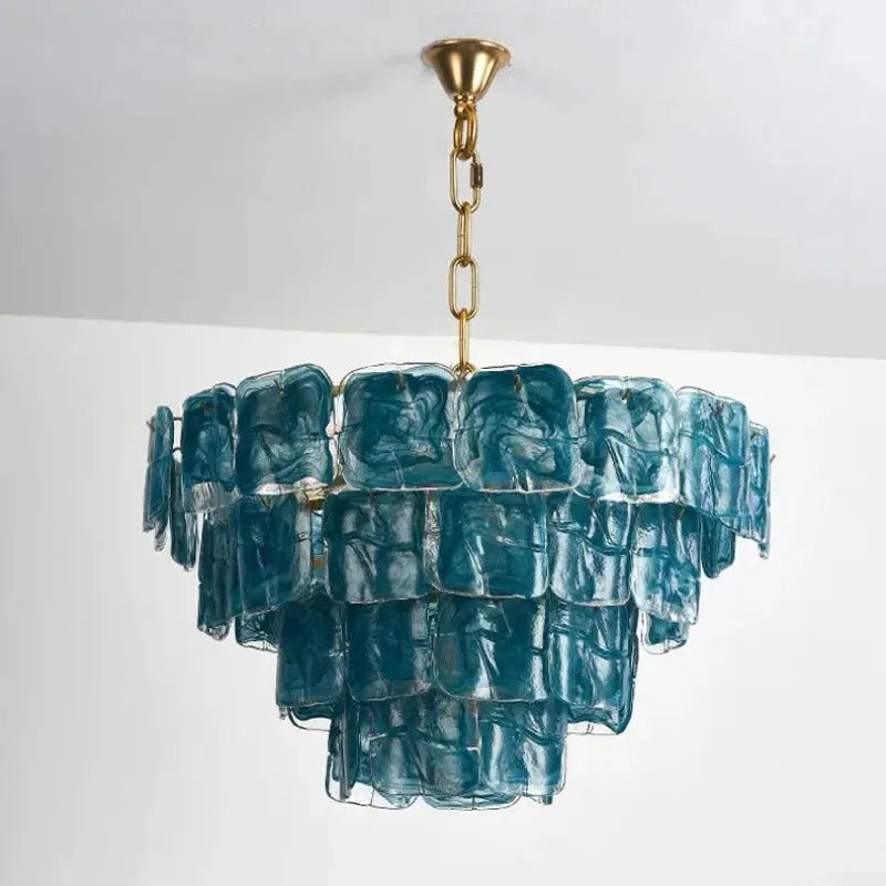 Blue glass chandelier with gold chain against a white background